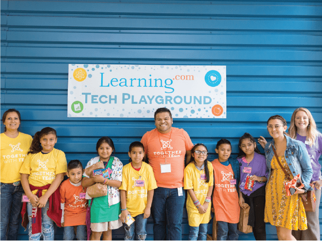Group of students and teachers under learning.com tech playground sign