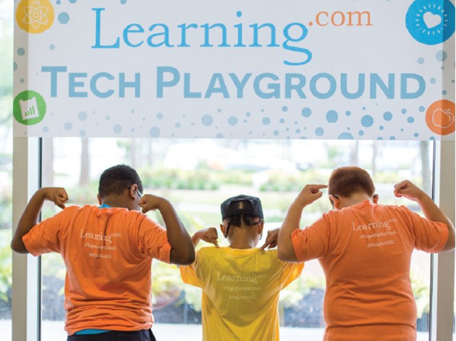 Three kids with backs facing camera flexing muscles under Learning.com tech playground sign