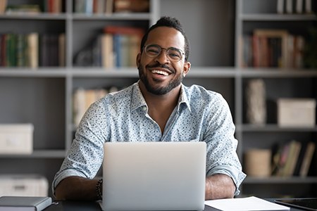 Man sitting at computer looking at camera and smiling