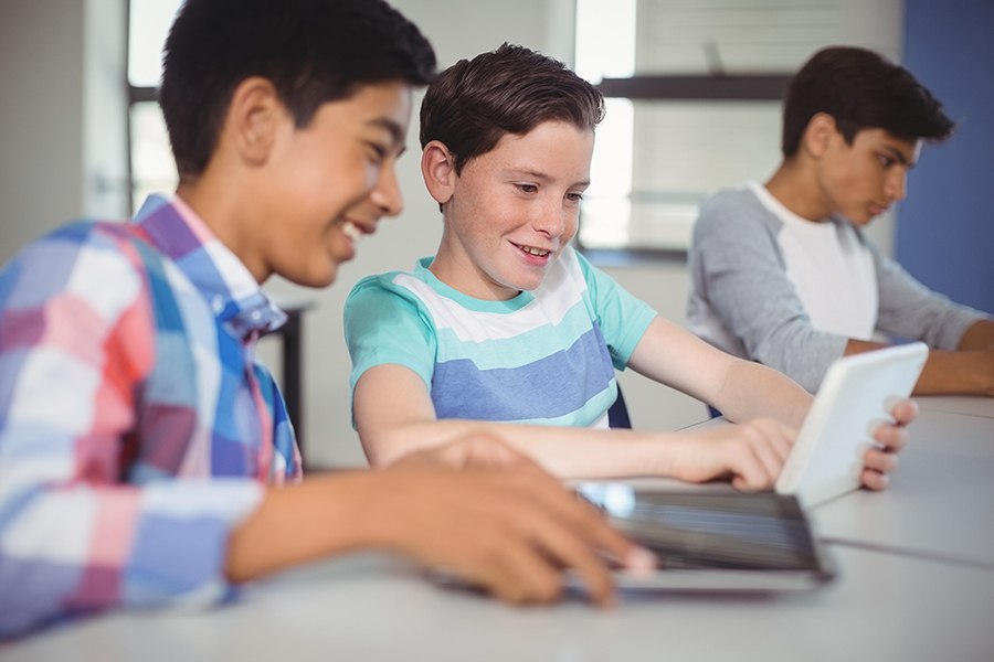 boys taking online coding program from learning.com on tablets at middle school