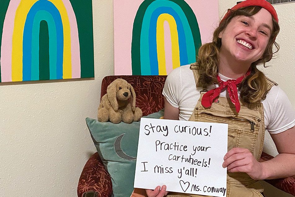 First Grade Teacher Holding Stay Curious Sign and Smiling at Camera