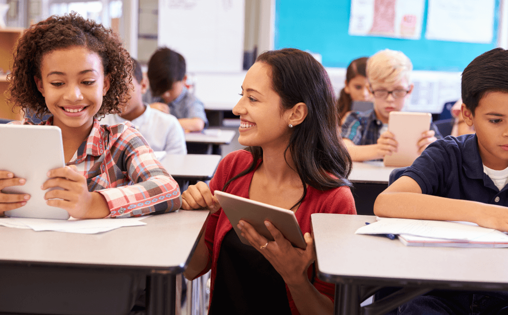 Teacher between students holding tablet