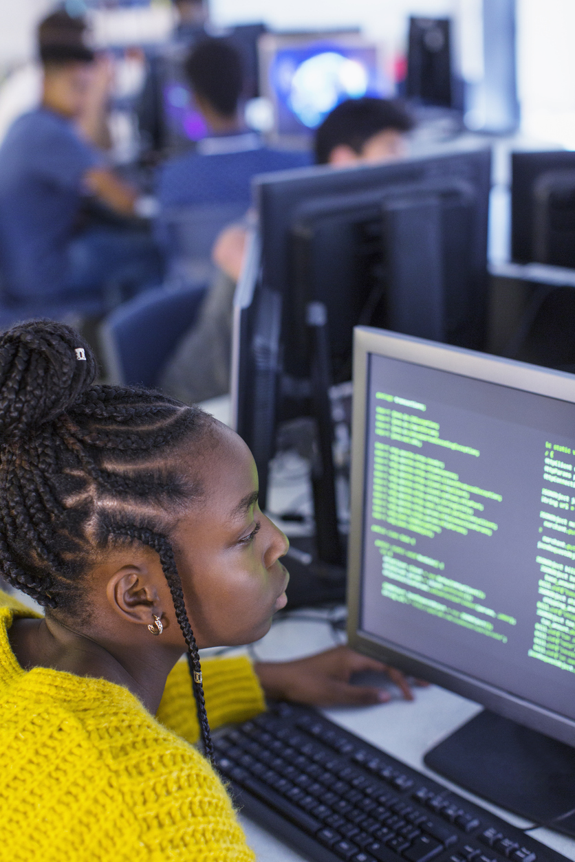 Female junior high student applying coding lessons on computer