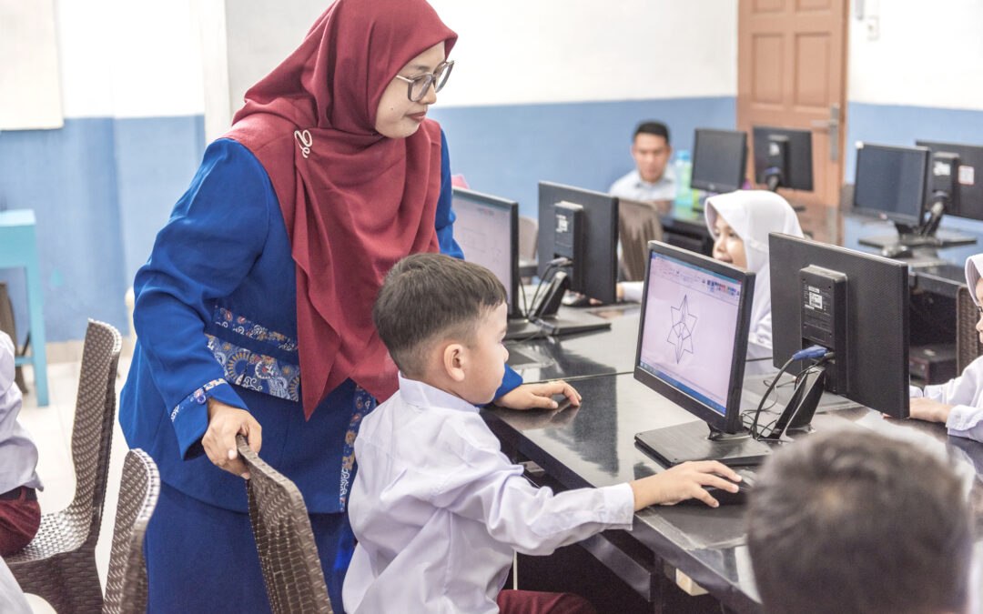 Teacher teaching computer coding to elementary student in computer classroom