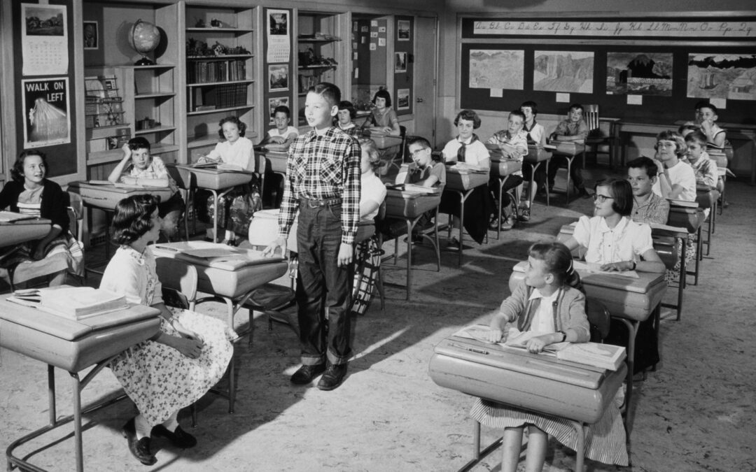1956 photo of classroom with boy standing beside desk to represent historical progression of personalized learning in classroom