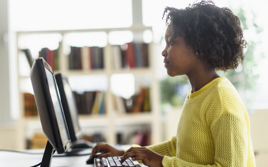 Black student in school library typing on computer