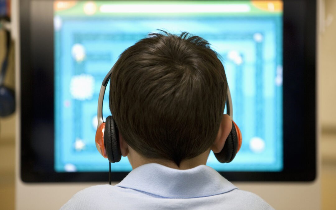 Young male student in front of computer in school computer lab practicing digital literacy skills