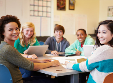 Two young female students thinking like programmers on a laptop in a classroom