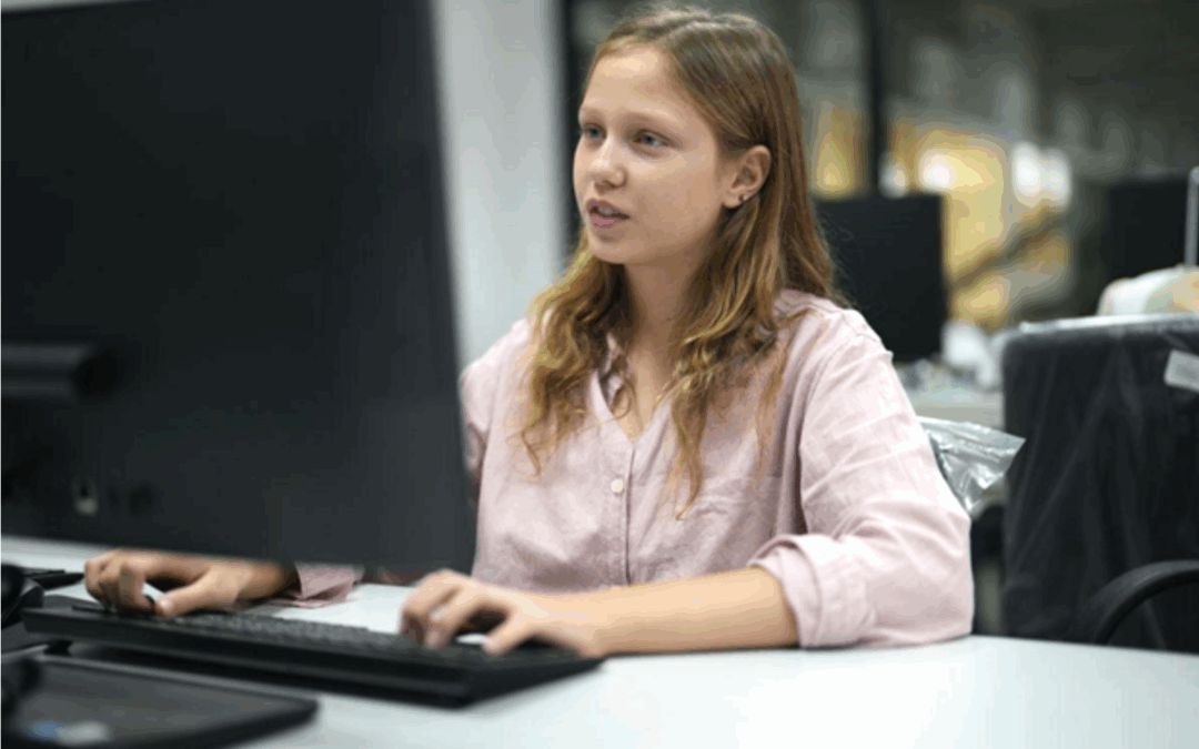Young girl at a computer engaged in AI lessons in a modern classroom setting