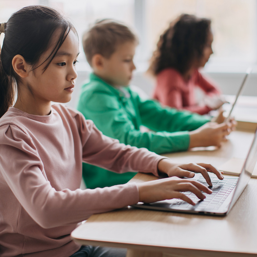 Female teacher in business suit holding tablet used for AI curriculum and looking at camera and smiling