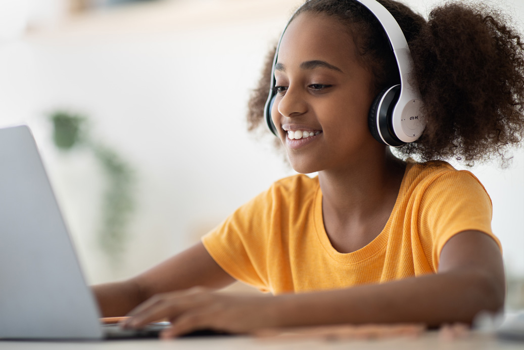 Elementary-age students smiling at laptop as they use AI safely to learn new topics in school