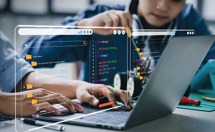 Smiling teacher assisting a student at a computer in a classroom setting